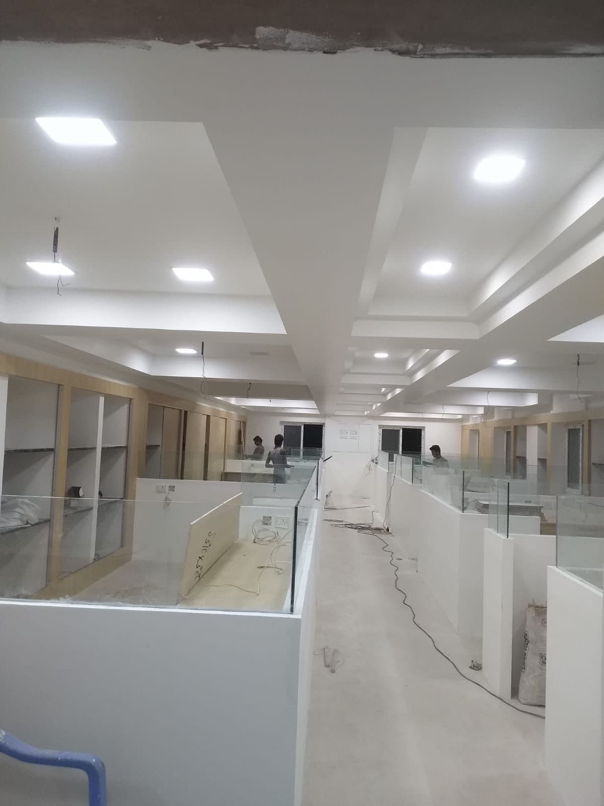 The same office floor during fit-out, with the glass partitions in place, cabling still run loose and workers on the floor beyond.