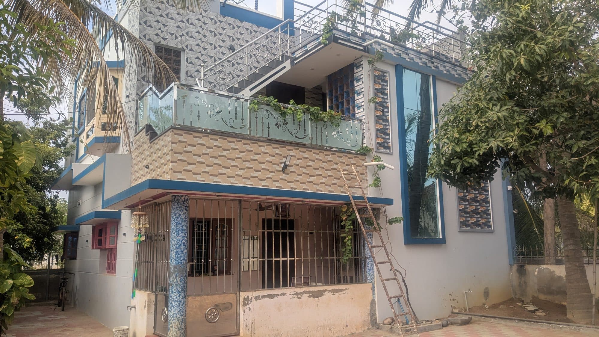 Closer view of the same residence showing the two cladding tile patterns, the glazed stair tower, the etched glass balcony panel and the mosaic-clad verandah columns.