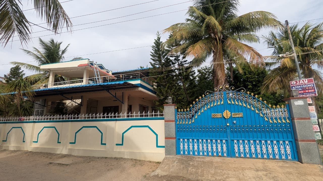 The blue and gold double-leaf gate hung on granite-faced piers, with mild-steel railing running above the compound wall.